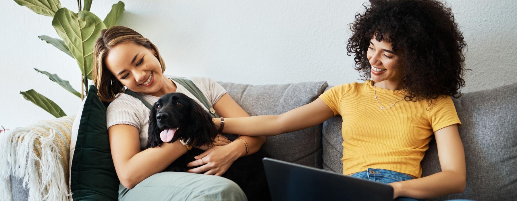 a couple of women sitting on a couch with a dog