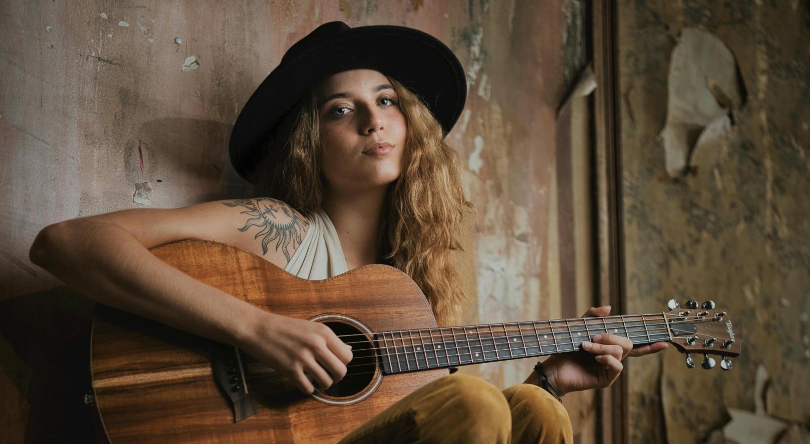 Settle into comfort at San Marin Apartments woman with long hair and a hat playing a guitar