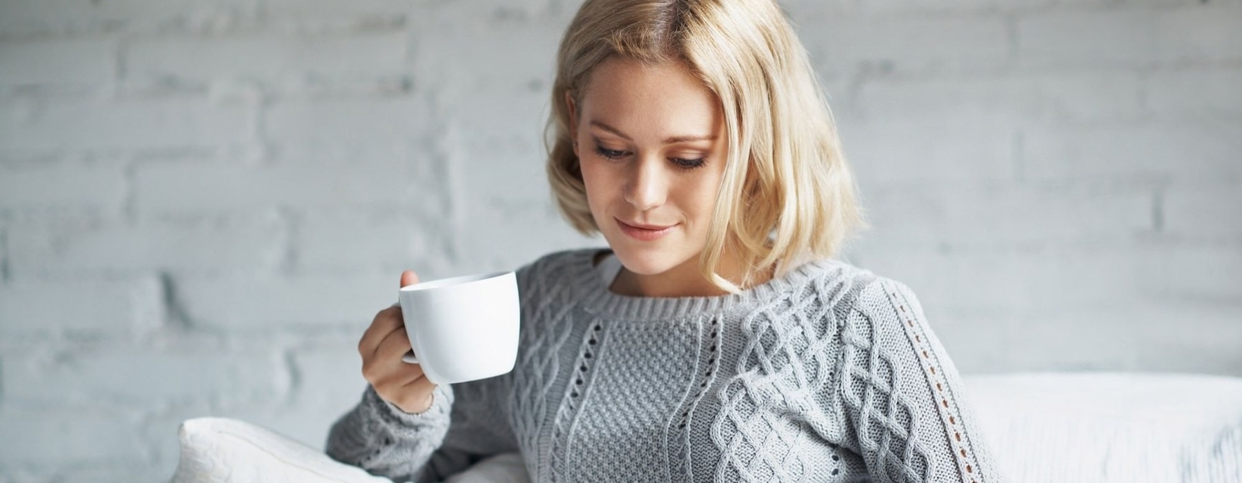 Woman sitting in a living room drinking coffee