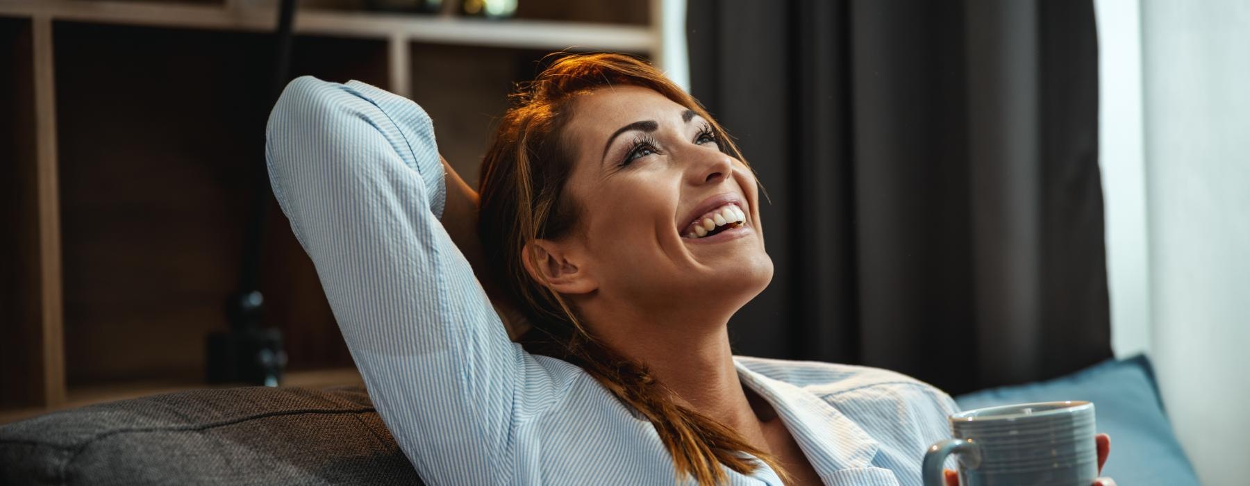 a woman laughing while holding a cup